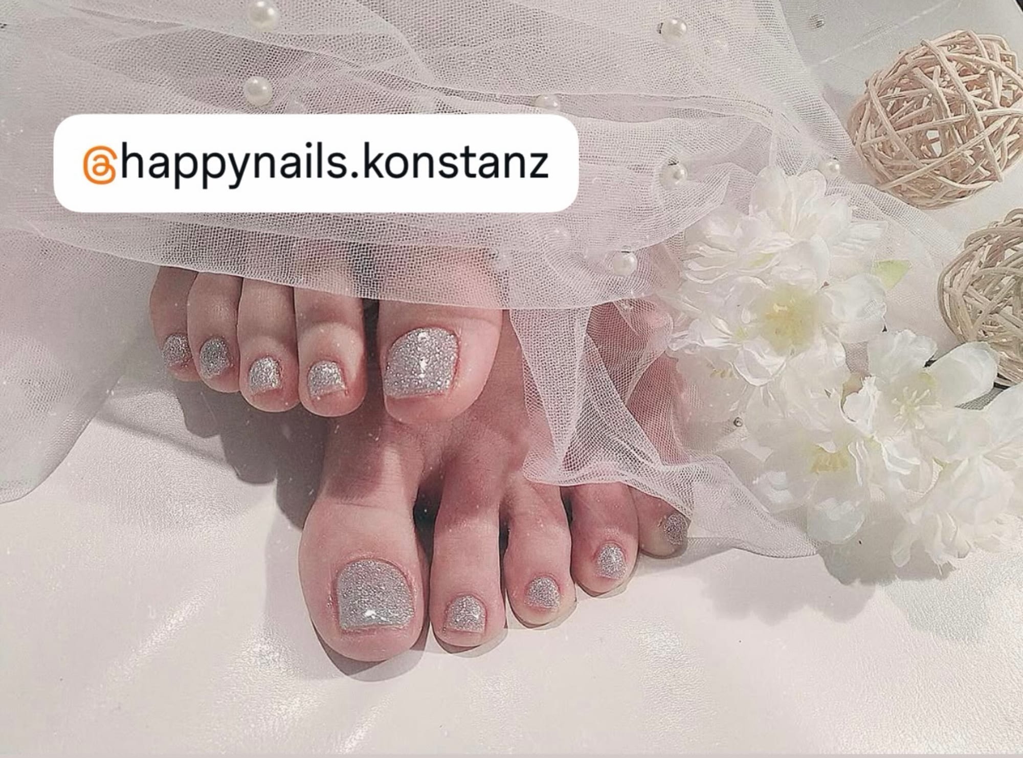 Glitzer-Maniküre mit weißen Blüten